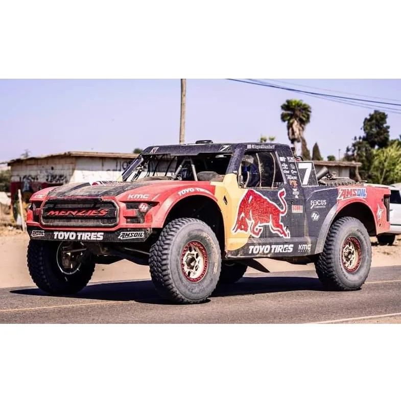 Off-road racing truck with Red Bull branding on rugged terrain.