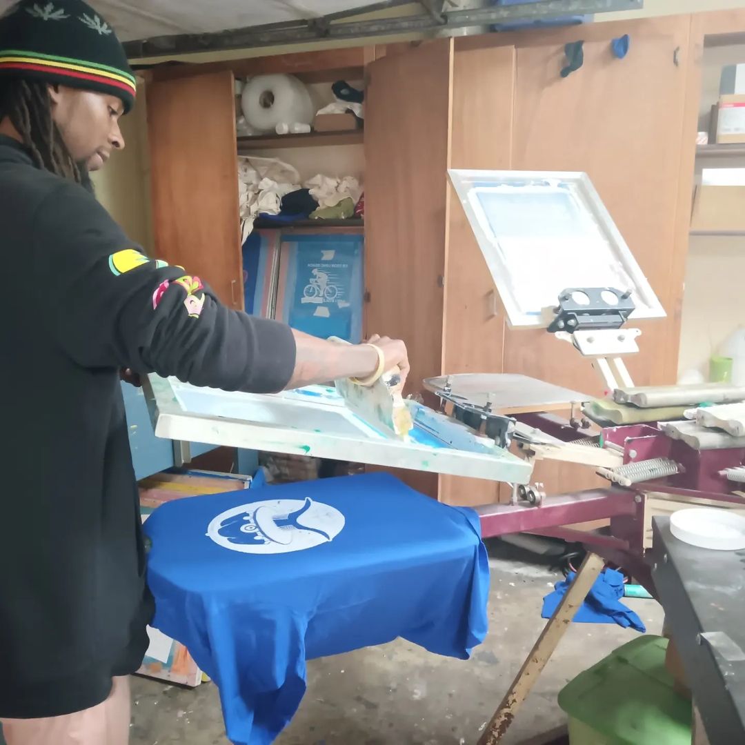 Person printing a design on a blue t-shirt using a heat press.