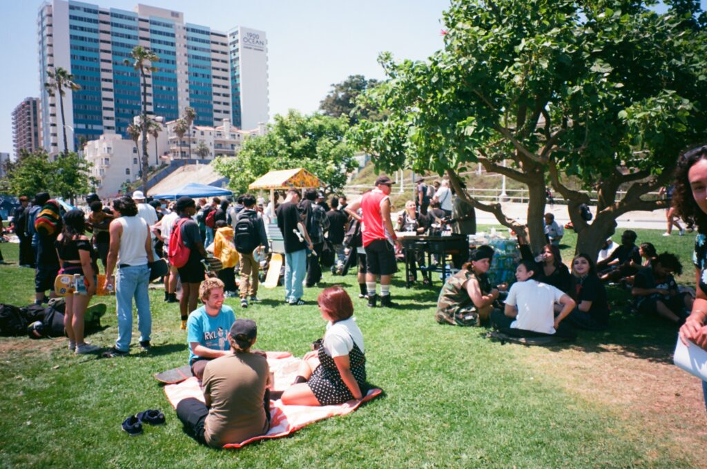 People enjoying a sunny day at a lively outdoor event in a city park.