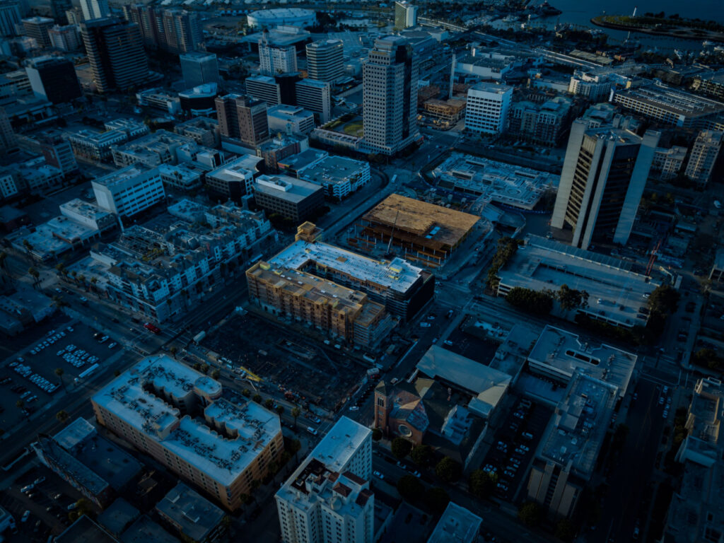 Aerial view of a cityscape at dusk with illuminated buildings and streets.