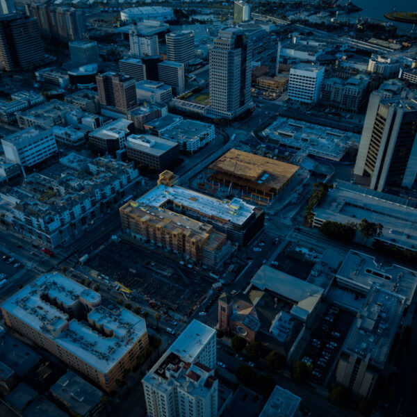 Aerial view of a cityscape at dusk with illuminated buildings and streets.