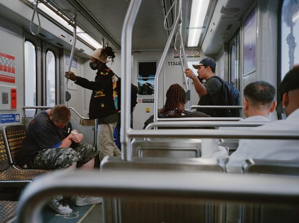 People riding a subway train with one person standing and holding a pole.